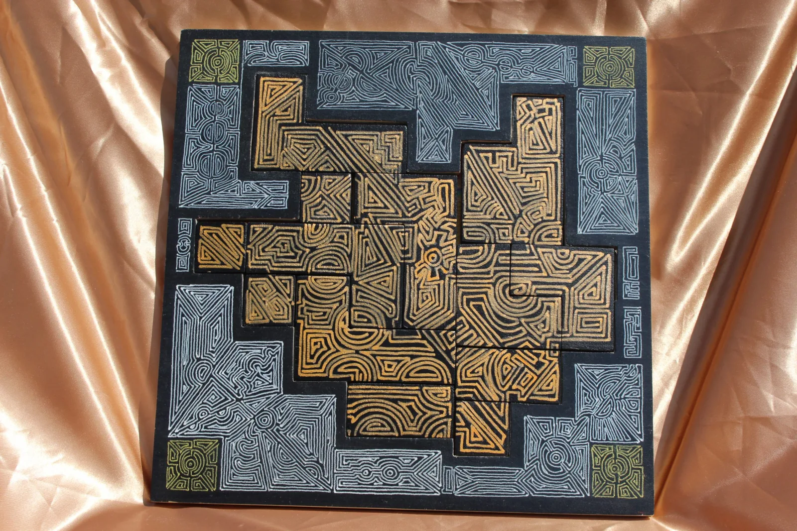 Casse-tête carré gravé de motifs labyrinthiques dorés et gris ardoise, sur tissu cuivré
