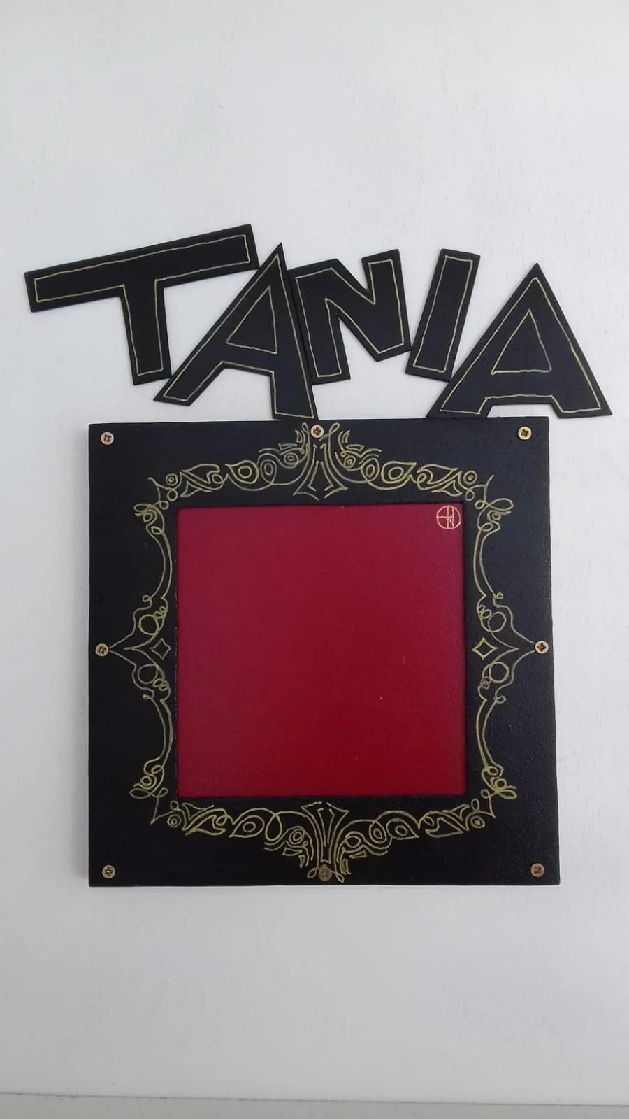 Casse-tête personnalisé au prénom TANIA : lettres noires découpées au-dessus d'un cadre noir orné de dorures