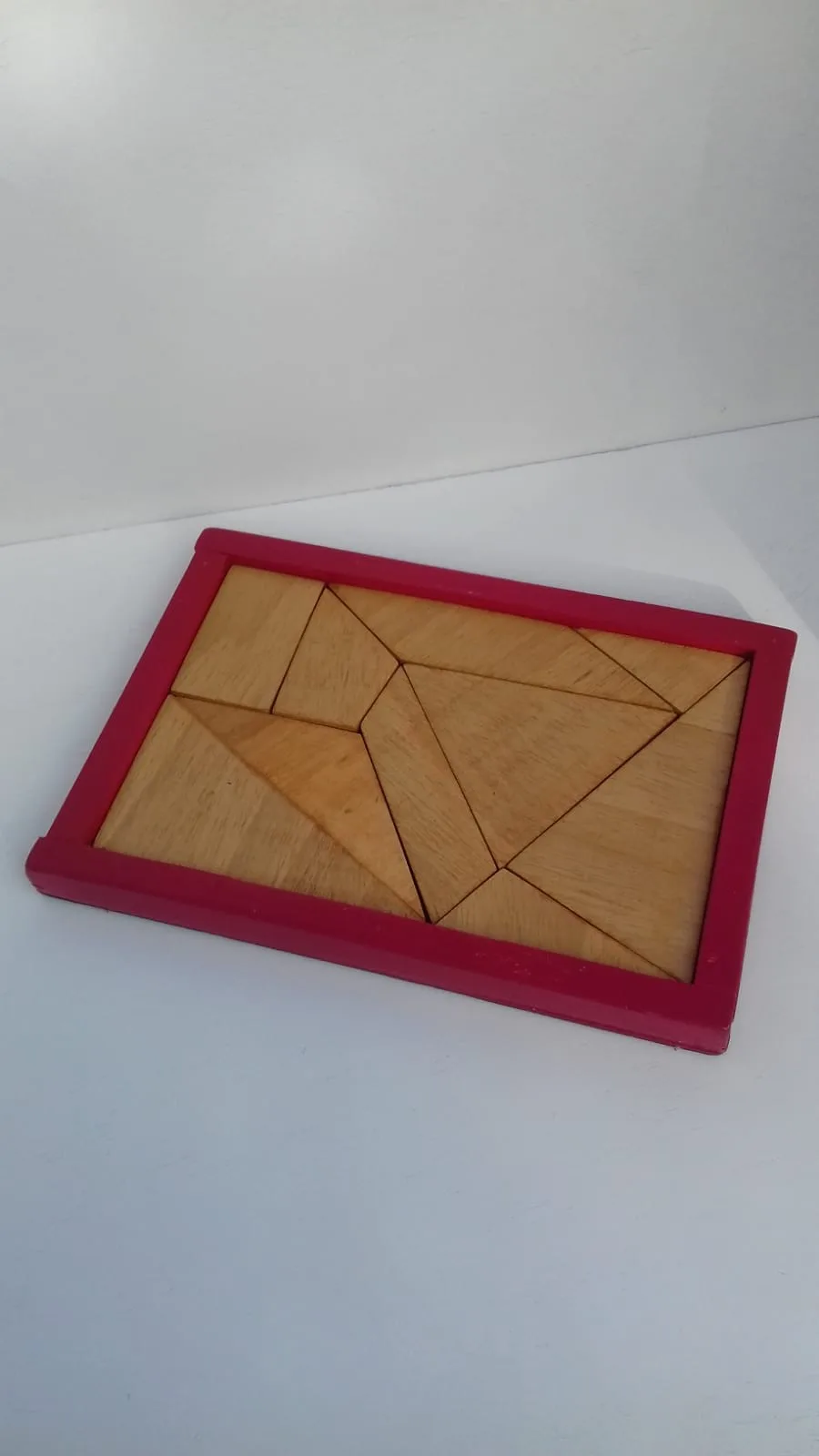 Casse-tête Le coriace : pièces triangulaires en bois clair dans un cadre rose framboise