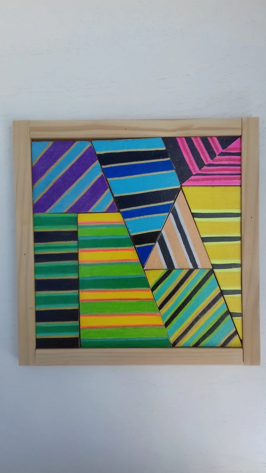 Casse-tête Le réversible : pièces triangulaires à rayures multicolores dans un cadre en bois clair