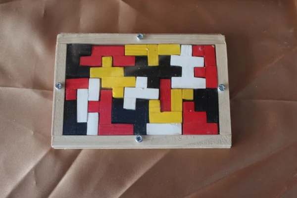 Casse-tête La Fresque Urbaine : pièces rouges, jaunes, noires, blanches et grises dans un cadre rectangulaire en bois clair