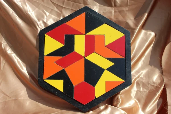Casse-tête Solstice : pièces triangulaires rouges, orange et jaunes formant une étoile dans un cadre hexagonal noir
