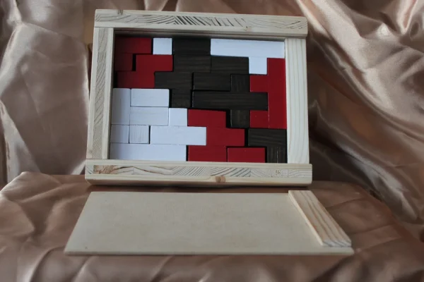 Casse-tête Triptyque : pièces rouges, noires et blanches dans un coffret en bois clair à couvercle coulissant